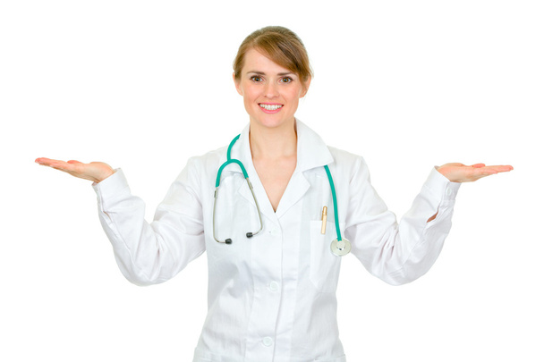 Smiling medical doctor woman presenting something on empty hands - Fotó, kép