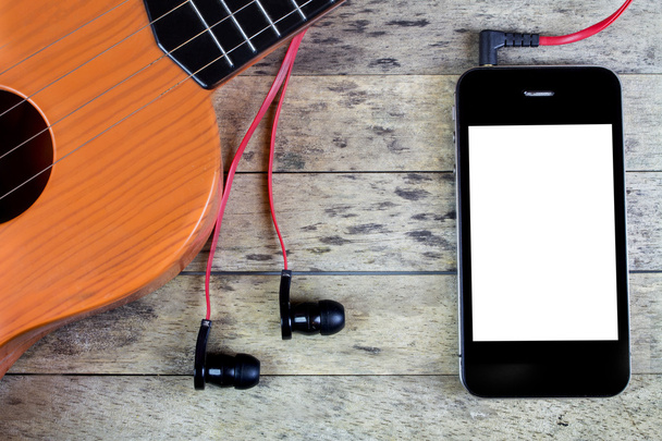 Guitarra, fones de ouvido e telefone inteligente em uma mesa de madeira
 - Foto, Imagem