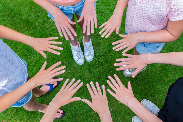 Many children hands joining in circle above grass - Photo, Image