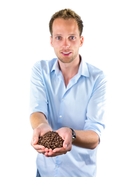 Jovem vendedor mostrando as mãos cheias de grãos de café
 - Foto, Imagem