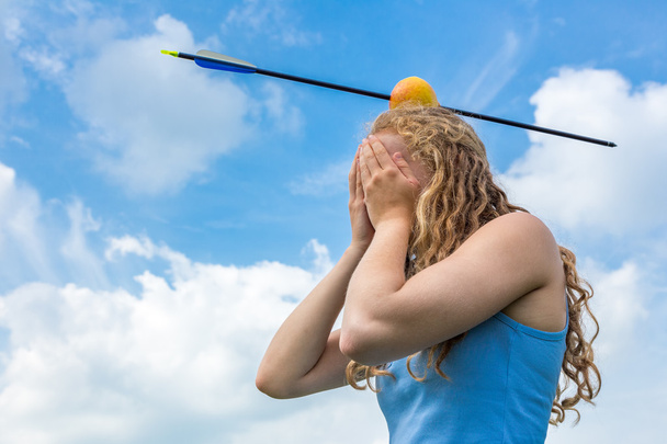 Teenage girl feeling fear with apple and arrow on head - Photo, Image