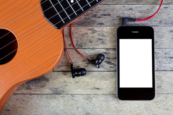 Guitar, earphones and smart phone on a wood table - Photo, Image