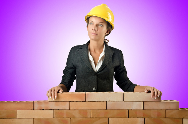 jonge vrouwelijke bouwer in de buurt van bakstenen muur - Foto, afbeelding