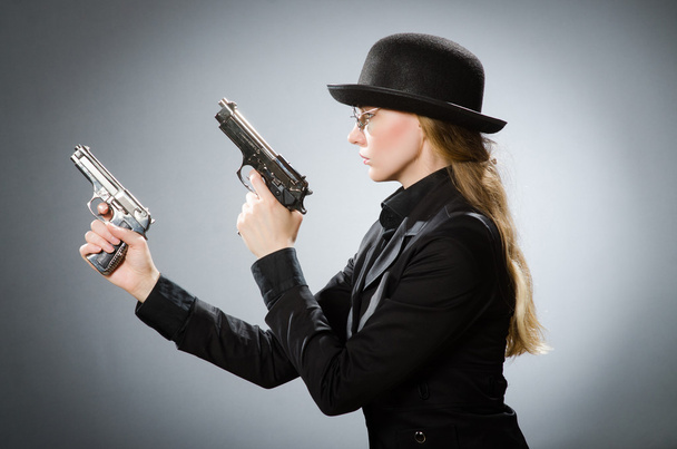 Female spy with weapon against gray - Photo, Image