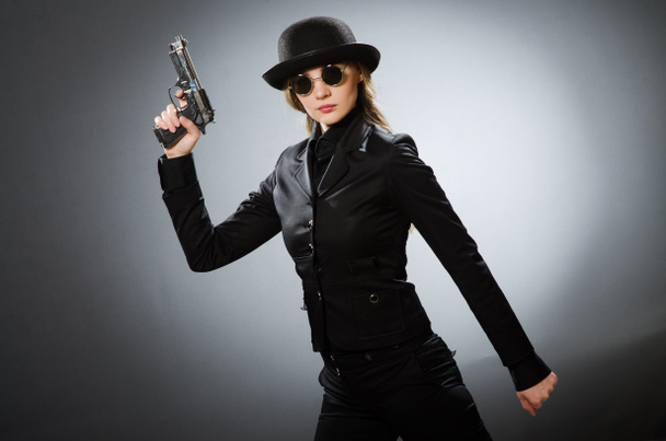 Female spy with weapon against gray - Photo, Image
