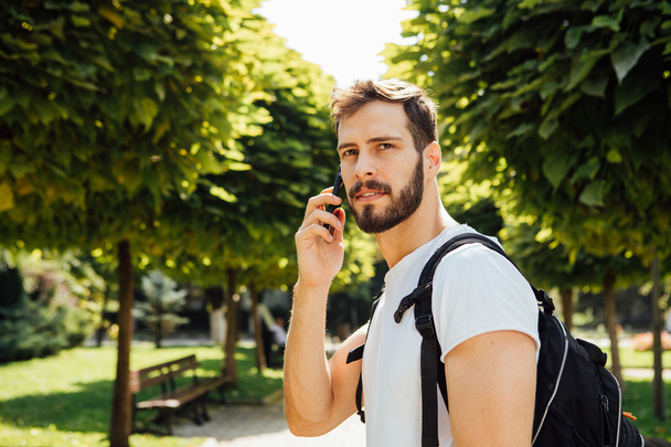 Student with backpack talking at cellphone - 写真・画像