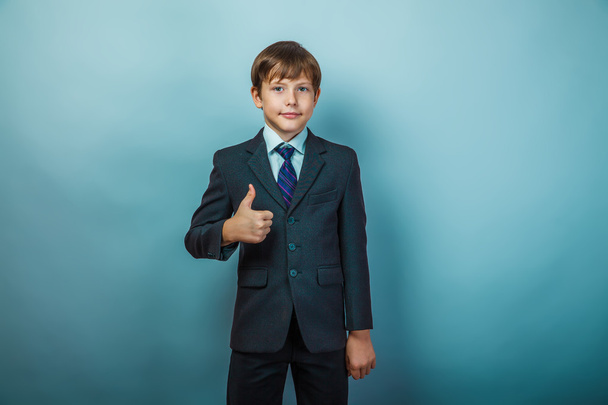 Eurooppalainen ulkonäkö teini-ikäinen poika yrityspuvussa osoittaa merkin
 - Valokuva, kuva