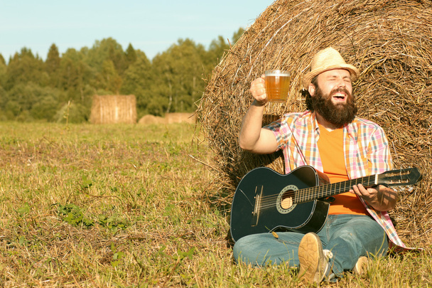 άνθρωπος με κιθάρα και μπύρα στη φύση - Φωτογραφία, εικόνα