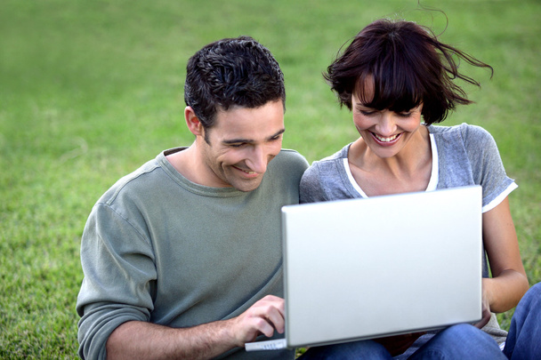 Couple sat with laptop in the park - Photo, Image