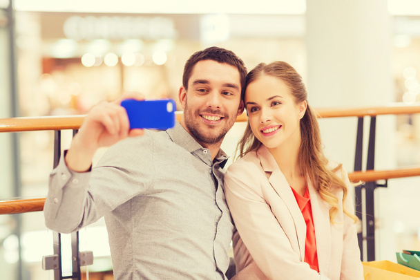 happy couple with smartphone taking selfie in mall - 写真・画像