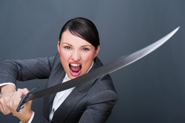 Business woman showing determination while holding a sword - Foto, Imagen