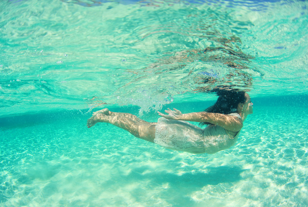 モルディブの島の近くの海でのダイビングのドレスで美しい若い女性 - 写真・画像