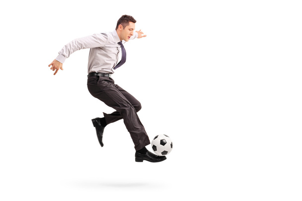Young businessman kicking a football  - 写真・画像