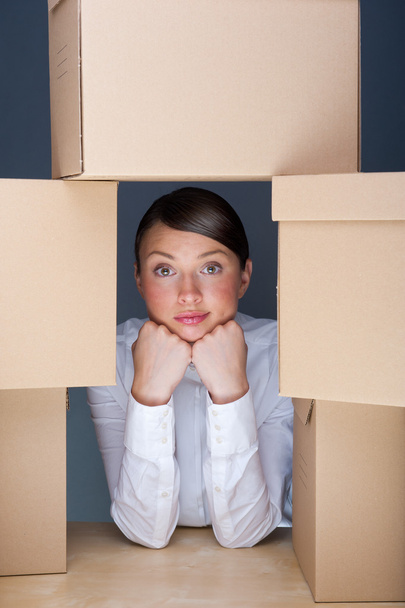 Portrait of young woman surrounded by lots of boxes. Lots of wor - Фото, изображение