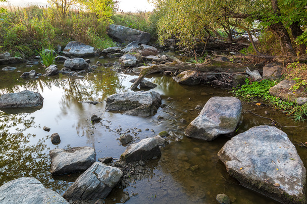 Ορμητικά σημεία ποταμού πέτρα στις όχθες του ποταμού στις ακτίνες της Ανατολής του ήλιου. - Φωτογραφία, εικόνα