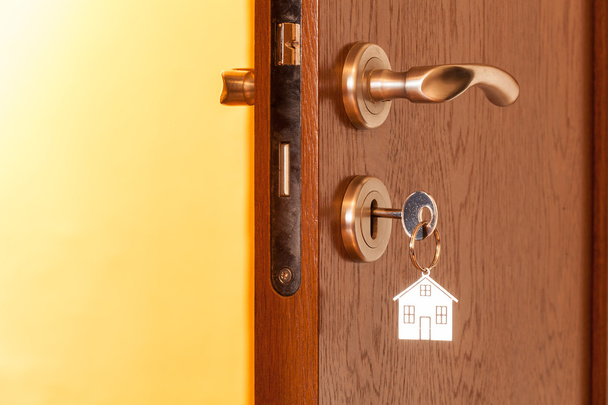 дверная ручка с вставленным ключом в замочную скважину и иконкой дома на ней
 - Фото, изображение