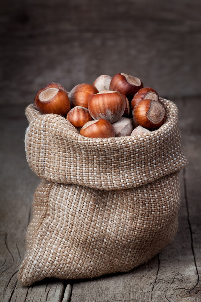 hazelnuts in bag on wooden table - Фото, изображение
