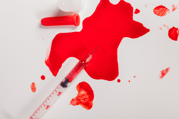 Syringe Squirting Red Blood onto White Background - Photo, image