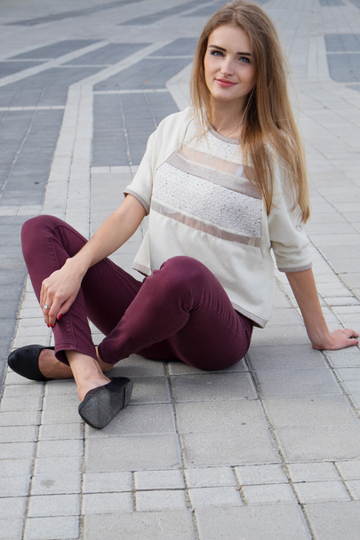 Cute blonde girl with long hair sitting on the floor - Фото, изображение