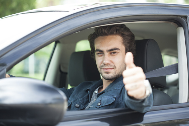 Młody człowiek kciuki gest w samochodzie - Zdjęcie, obraz