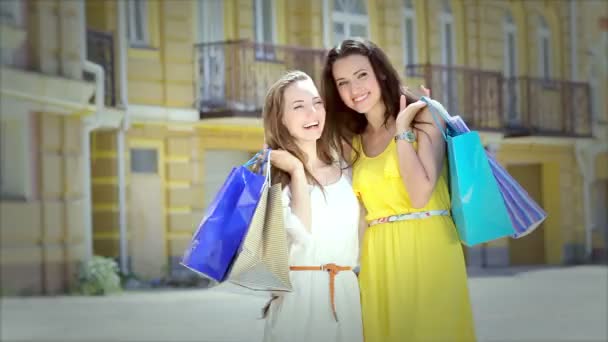 Two cheerful girls walking boutiques back to us then turn around to face us - Footage, Video