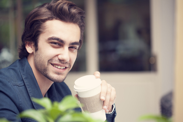 Young man drinking coffee in cafe - Фото, зображення