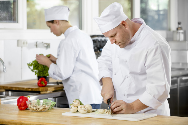 Due chef professionisti che preparano verdure in una grande cucina
 - Foto, immagini