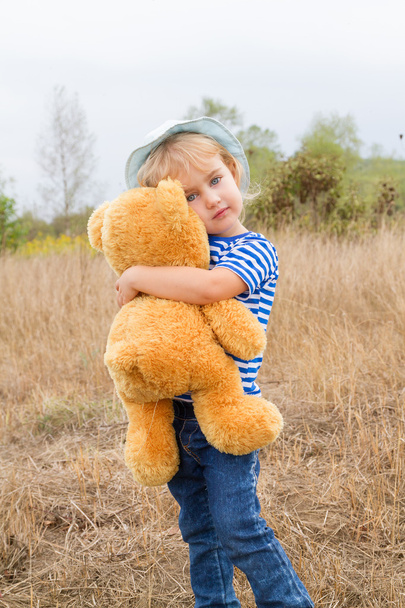 niedliches kleines Mädchen umarmt einen großen Teddybär - Foto, Bild
