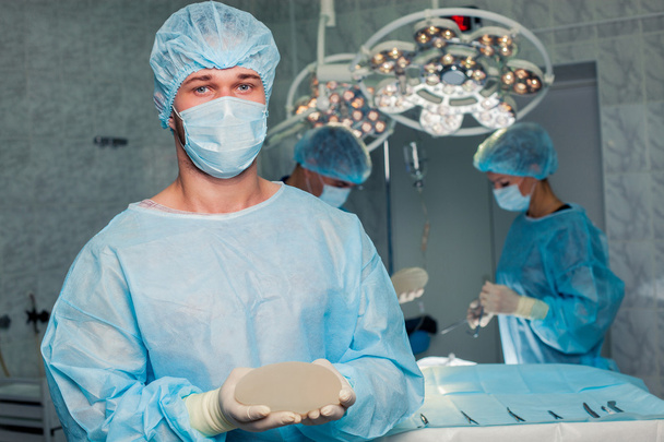Zespół lekarza w pracy w sali operacyjnej. Powiększanie piersi. - Zdjęcie, obraz