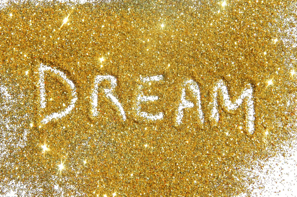 Wazig inscriptie droom op goud glitter sparkle op witte achtergrond - Foto, afbeelding