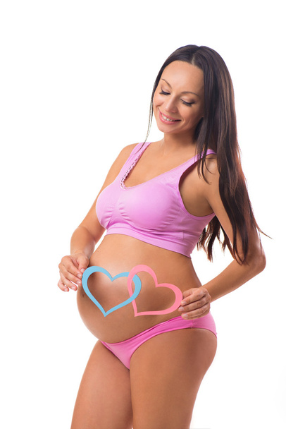 Zwangerschap, moederschap. Wie is geboren: meisje, jongen of tweeling. Zwangere moeder houden van roze en blauwe hart op de buik. - Foto, afbeelding