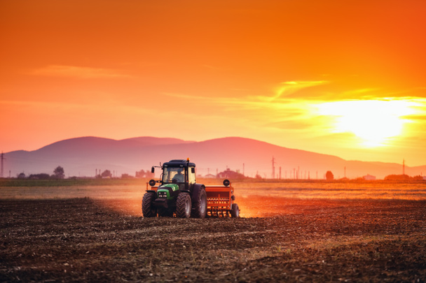 Beautiful sunset, farmer in tractor preparing land with seedbed - Foto, Bild