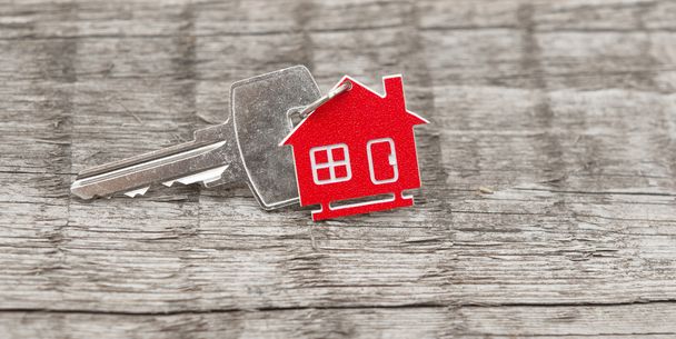 Symbol des Hauses mit silbernem Schlüssel auf Holzgrund - Foto, Bild