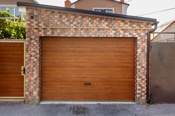 Деревянная дверь гаража на фоне кирпичной стены
 - Фото, изображение