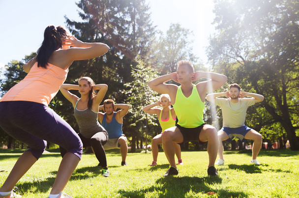 group of friends or sportsmen exercising outdoors - 写真・画像