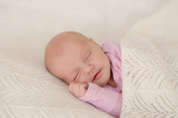 生まれたばかりの赤ちゃんの睡眠が満足し、笑みを浮かべて白い毛布で覆われて - 写真・画像