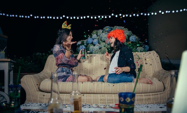 Feliz pareja de mujeres divirtiéndose entre la fiesta de confeti
 - Foto, Imagen
