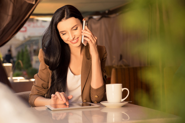 Красивая молодая деловая женщина в кафе разговаривает по телефону и
 - Фото, изображение