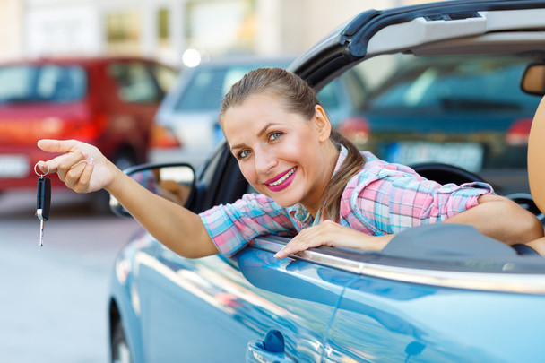 Young  woman sitting in a convertible car with the keys in hand - Photo, Image