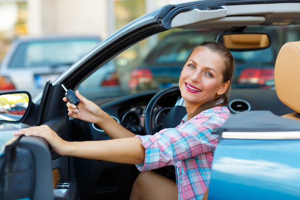 Young  woman sitting in a convertible car with the keys in hand - Foto, imagen