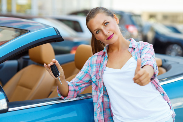 junge glückliche Frau steht neben einem Cabrio mit den Schlüsseln in h - Foto, Bild