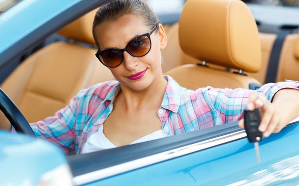 Mujer en gafas de sol sentada en un coche convertible con las llaves i
 - Foto, imagen