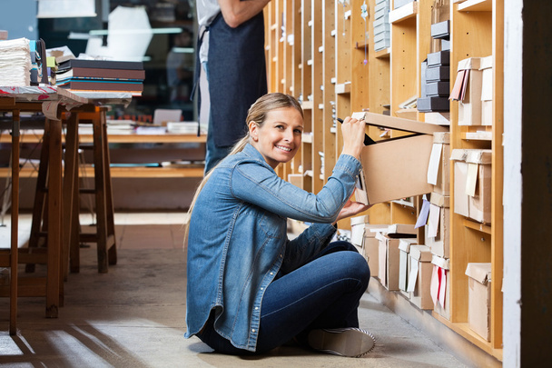Happy Female Customer Removing Box From Shelf In Shop - Foto, Imagem
