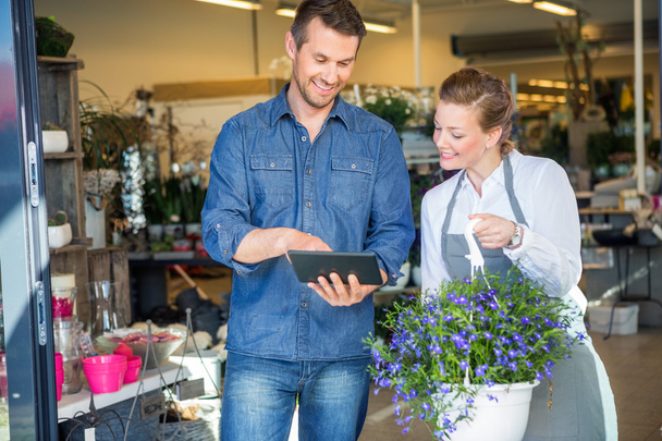Customer Using Digital Tablet While Standing By Florist - 写真・画像