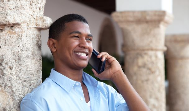 Laughing latin guy with phone in a colonial town - Foto, Imagen