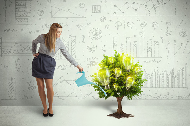 Business woman pouring water on lightbulb growing tree - Photo, Image