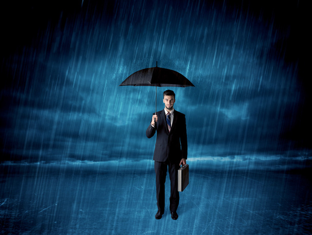 Business man standing in rain with an umbrella - Фото, изображение