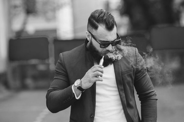 mies, jolla on parta polttaa sähkösavuketta
 - Valokuva, kuva