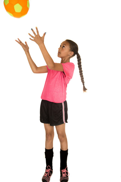 Young girl in soccer uniform catching a soccer ball - Фото, зображення