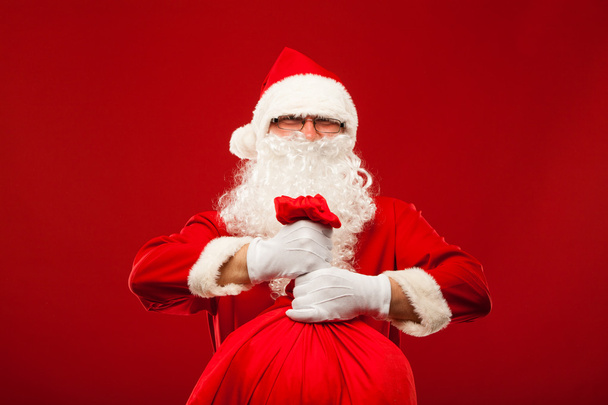 santa claus with big bag on shoulder glasses  red background - Foto, immagini